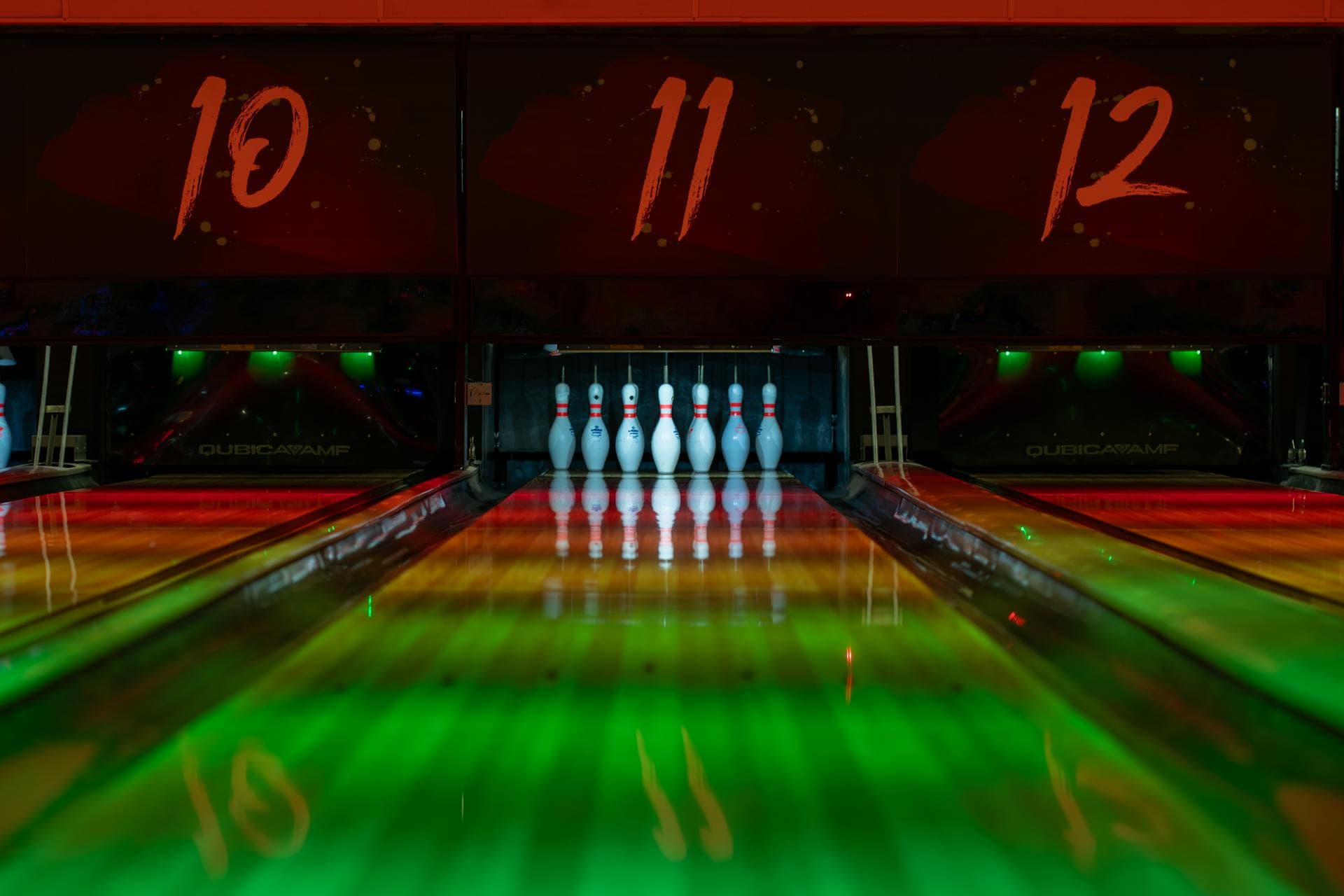 Pins lit by red and green house lighting at the end of the lane